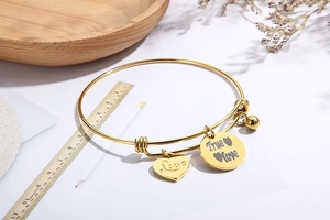 Detailopname van verstelbare roestvrijstalen armband met hart en Love bedeltjes