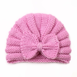 Close-up of pink knitted baby hat featuring a large decorative bow and soft yarn texture