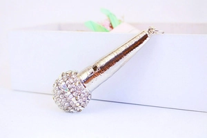 Close-up of a silver microphone keychain with sparkling rhinestones on a white surface