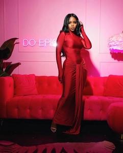 Détail d'une robe rouge élégante à manches longues, aspect soyeux et ceinture nouée
