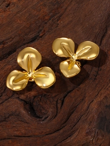 Detailed top view of gold flower earrings on dark wood background with metallic luster