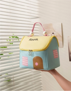 Dettaglio della borsa da toilette a forma di casa con manico di perle e testo Room