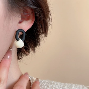 Gros plan de boucles d'oreilles géométriques élégantes noires et blanches sur un mannequin