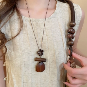 Detail of vintage resin heart pendant necklace with retro ethnic style on linen clothing