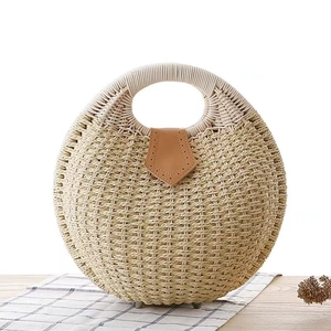 Detail of round straw handbag with circular handle and brown leather shield closure