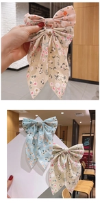 Close-up of floral print bow hair clips in pink and beige fabric with metal fasteners