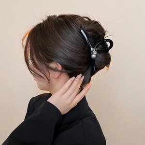 Close-up of elegant black hair claw clip with pearl and crystal on a bun hairstyle