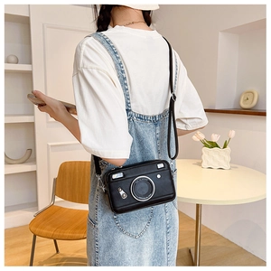 Detailed view of creative camera-shaped crossbody bag with lens detail on model