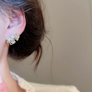 Detailed close-up of an elegant gold bow earring with sparkling zircon on a model's ear