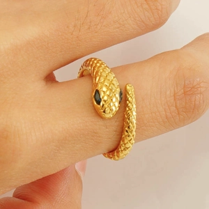 Macro detail of golden snake ring showing textured scales and black stone eyes