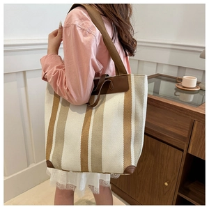 Detail of striped canvas tote bag with brown leather trim and spacious interior