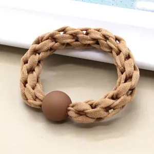 Detail of woven elastic hair tie in milk tea brown color with a matte spherical bead
