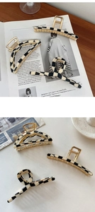 Close-up of geometric black and white checkered acetate hair claws with gold metal springs