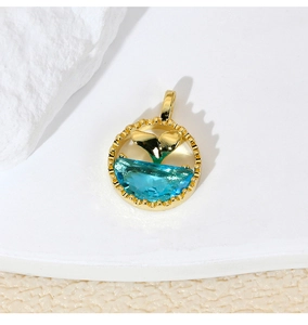 Detailed view of a gold dolphin tail pendant featuring a crescent blue gemstone on stone