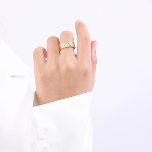 Détail d'une bague vintage en acier titane doré avec texture tressée sur un modèle