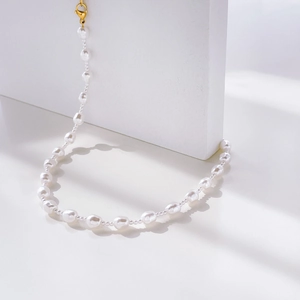 Detailed view of baroque pearl necklace with golden lobster clasp on a stone decor