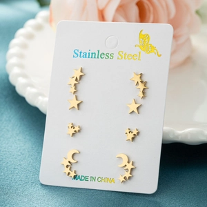 Three pairs of gold stainless steel star and moon stud earrings on a display card