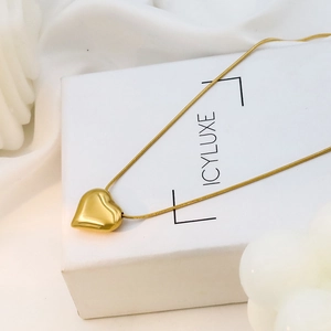 Detail of 18k gold heart pendant on snake chain over a white jewelry display box