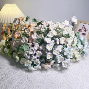 Handmade crochet flower bouquet featuring colorful pansies and lilies on lace tablecloth