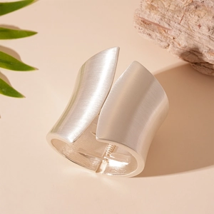 Detail of wide brushed silver cuff bracelet with hinge on natural stone backdrop