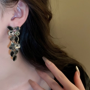 Close-up of a vintage dark drop earring with black crystals worn by a model
