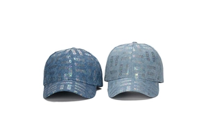 Close-up of denim baseball caps featuring holographic Queen lettering and washed texture