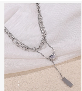 Detail of silver double layer necklace with thick and thin chains and geometric pendants