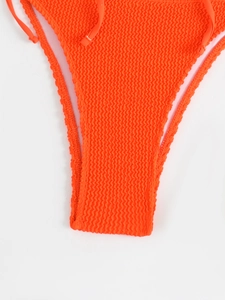 Detail of orange crinkle fabric bikini bottoms with side tie knots for beachwear