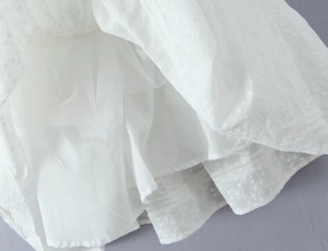Detailansicht der feinen Spitzenstickerei und Mesh-Lagen am weißen Kleid