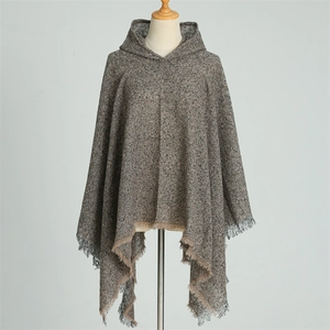 Close-up of brown knit hooded poncho featuring textured fabric and fringe tassel detail
