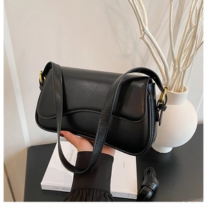 Detail shot of black leather underarm bag with gold buckles and adjustable shoulder strap
