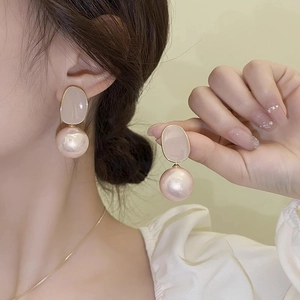 Elegant pearl flower earrings with gold metal and beige petal detail on model