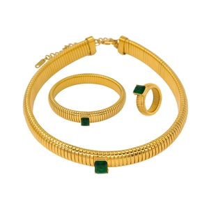 Close-up of gold jewelry set featuring emerald green zircon stones and striped texture