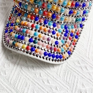 Detailed macro view of colorful pearls and sparkling rhinestones on a white baseball cap