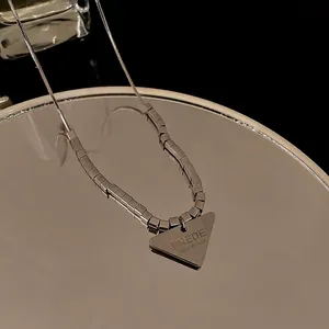 Collana minimalista argento con ciondolo triangolo e catena cubica su uno specchio