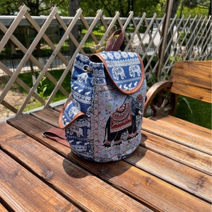 Ethnic blue canvas backpack with elephant pattern and drawstring closure on wooden table