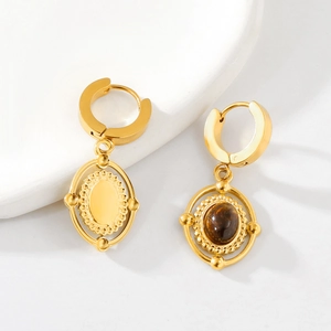 Macro shot of vintage gold earrings with oval tiger eye stones on white background