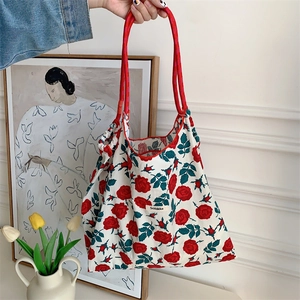 Detail of floral tote bag with red rose prints and thick red rope handles