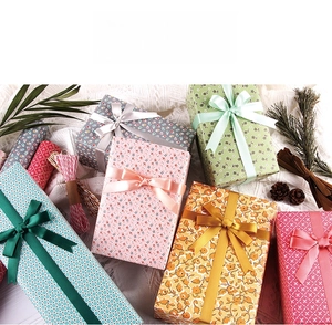 Vue de dessus de boîtes cadeaux pastel avec nœuds en ruban sur tissu blanc et pommes de pin