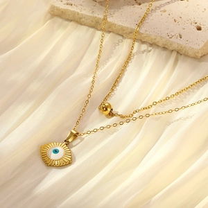 Detail of gold double-layer evil eye pendant necklace on elegant silk background