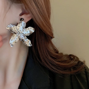 Close-up of a silver floral fan earring with hammered texture on a female model