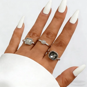 Close-up of stacked silver rings with gray cushions and clear square stones on model