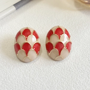 Close-up of oval vintage floral enamel earrings with red and cream scale patterns