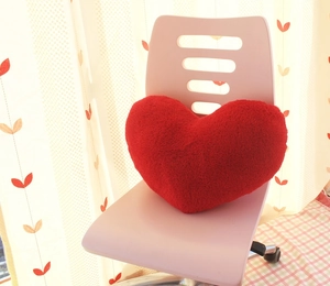 Close-up of soft red heart-shaped plush pillow on chair with fluffy long-hair texture