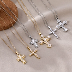 Detailed view of cross pendants with pearls on gold and silver chains over soft fabric