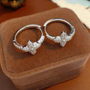 Detailed close-up of clover flower earrings with zircon inlays on brown velvet box