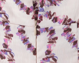 Detail of the hidden back zipper on a floral dress with abstract print on beige fabric
