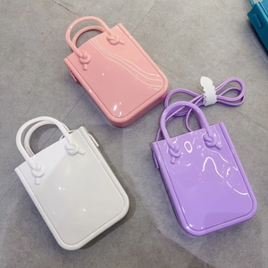 Three mini PVC jelly phone bags in pink, white, and purple colors on tile floor