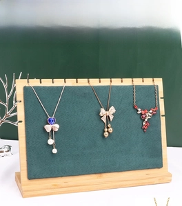 Bamboo jewelry display stand with green velvet backboard holding three elegant necklaces