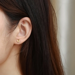 Elegant 18K gold plated heart stud earrings with radial texture on female model